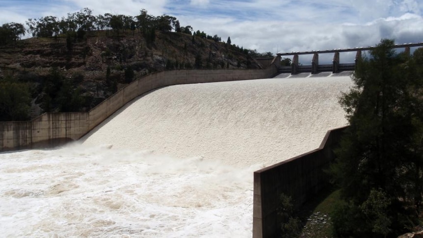 Water pours out of a dam from the top of a spillway down a slope