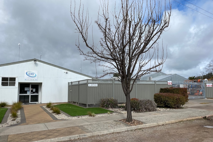 A white office building with a vehicle depot attached on a cloudy day in Horsham.