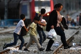 Syrian family walks across train tracks