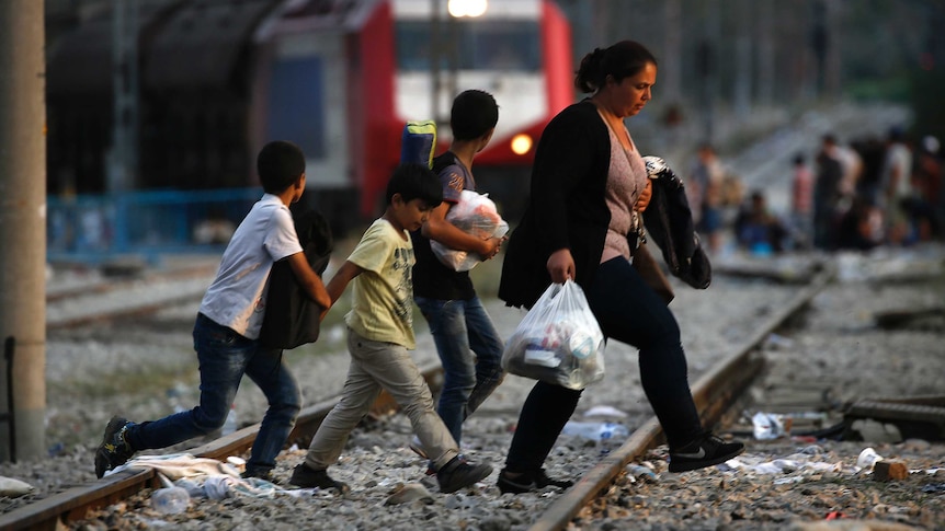 Syrian family walks across train tracks