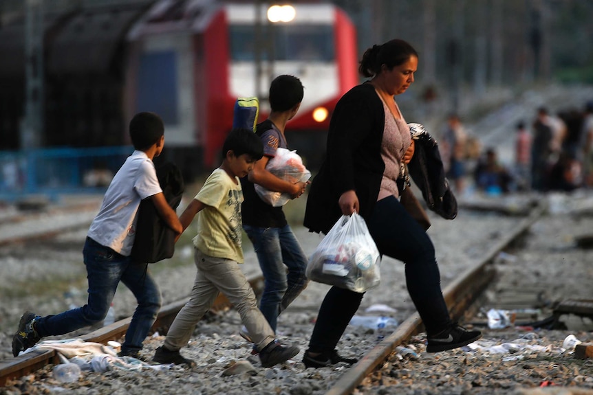 Syrian family walks across train tracks