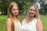 Tetiana and her daughter Dasha stand in a garden with trees in the background