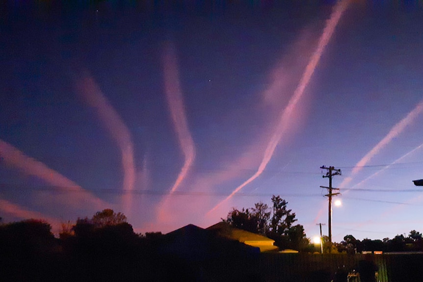 pink vapour trails over a house