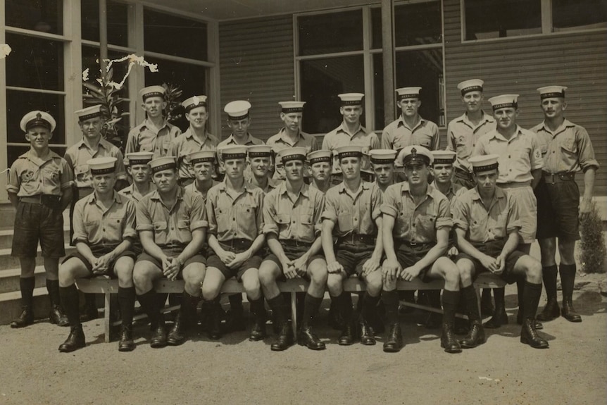 Black and white photo featuring three rows of men dressed in uniform.