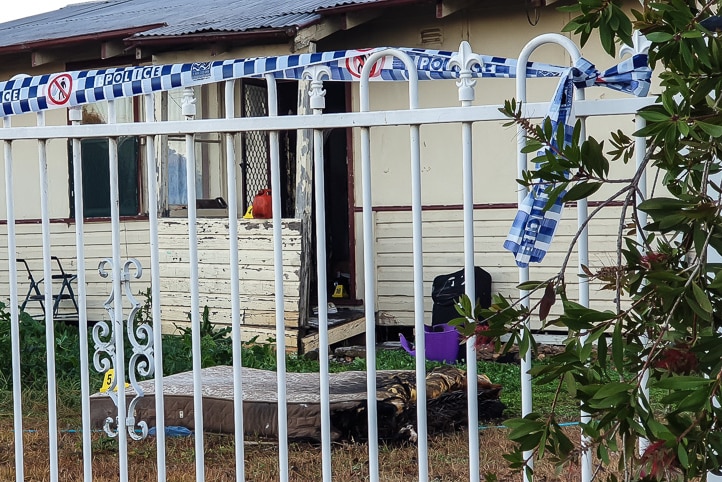 Police tape along a garden fence, a burned mattress in the front yard and other crime scene evidence at  house in Wellington NSW