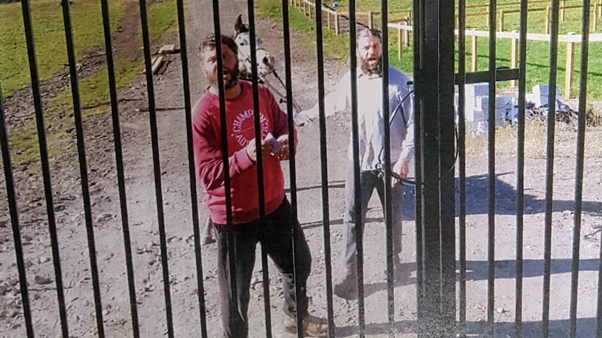 Two men behind a gate