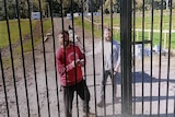 Two men behind a gate