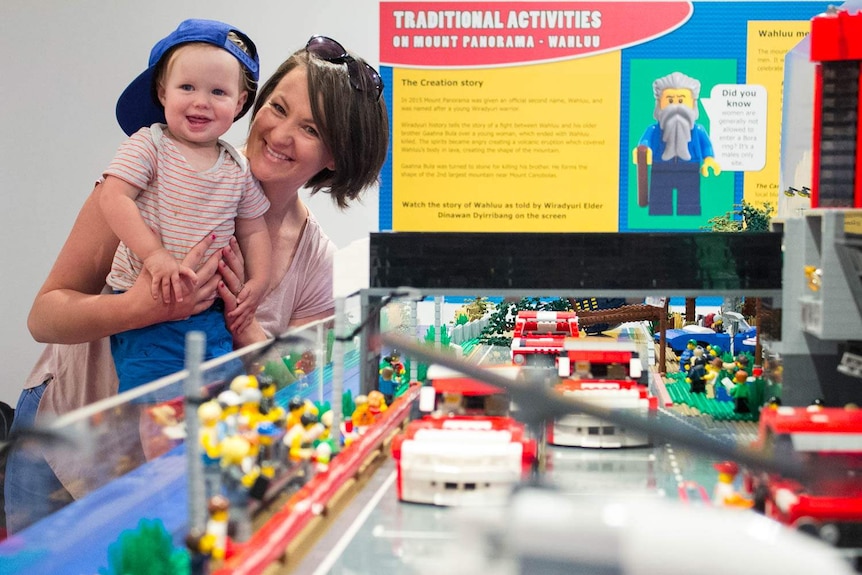 A mother and young boy looking at a lego model of a race track.