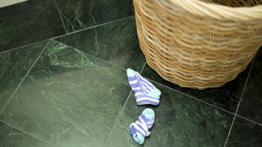 Children's socks lying next to a laundry basket.