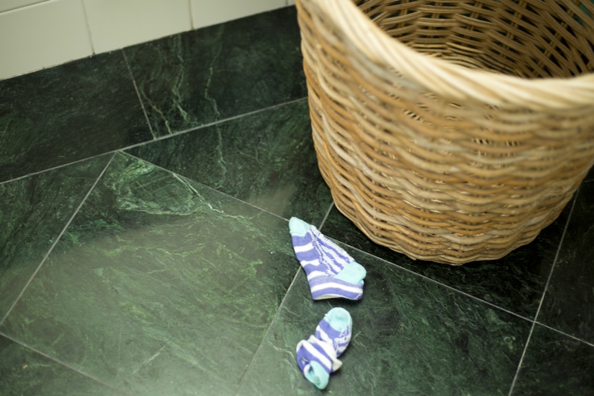 Children's socks lying next to a laundry basket.