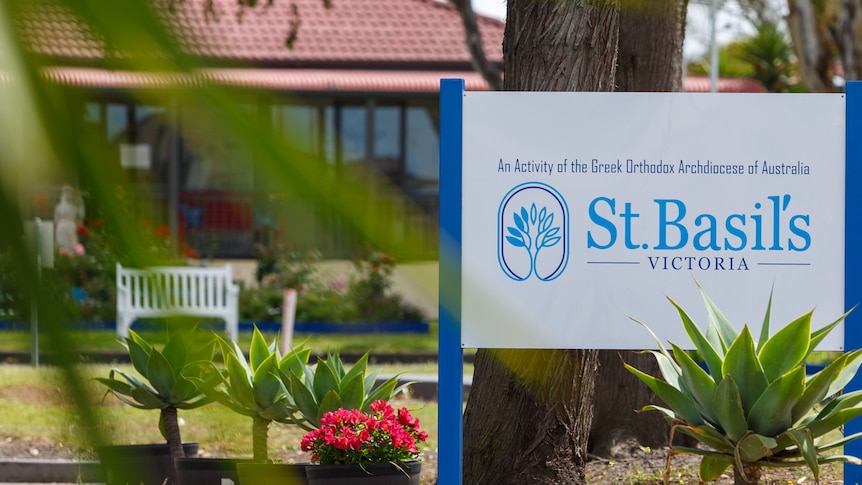 A blue and white sign that reads 'St Basils Victoria' in front of a building