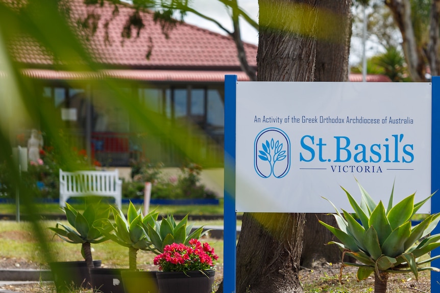 A blue and white sign that reads 'St Basils Victoria' in front of a building