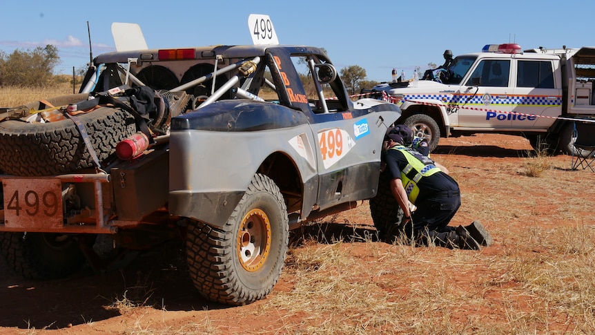 Police inspect a truck involved in a crash at the Finke Desert Race. 