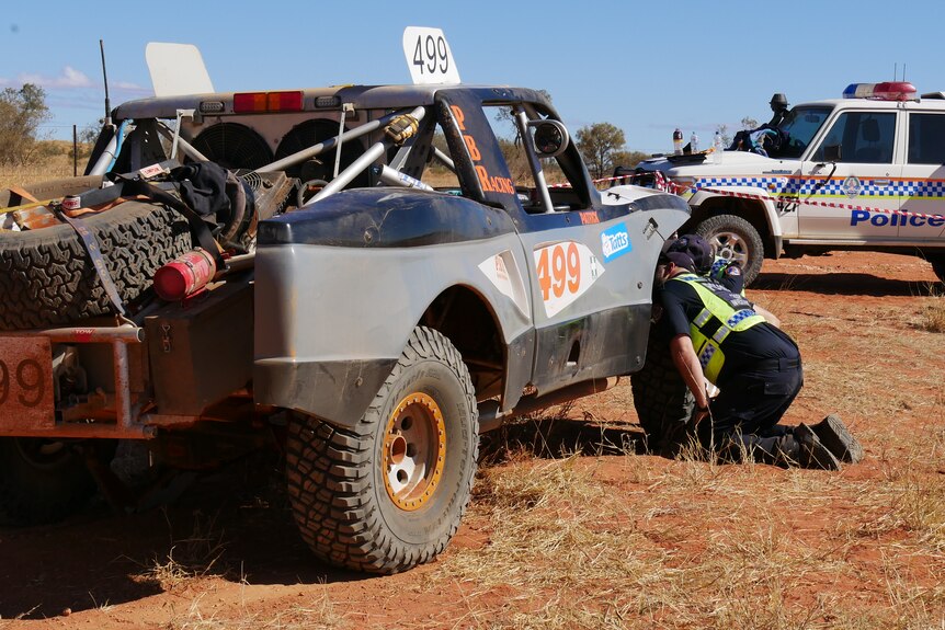 Police inspect a truck involved in a crash at the Finke Desert Race. 