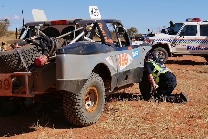 Police inspect a truck involved in a crash at the Finke Desert Race. 