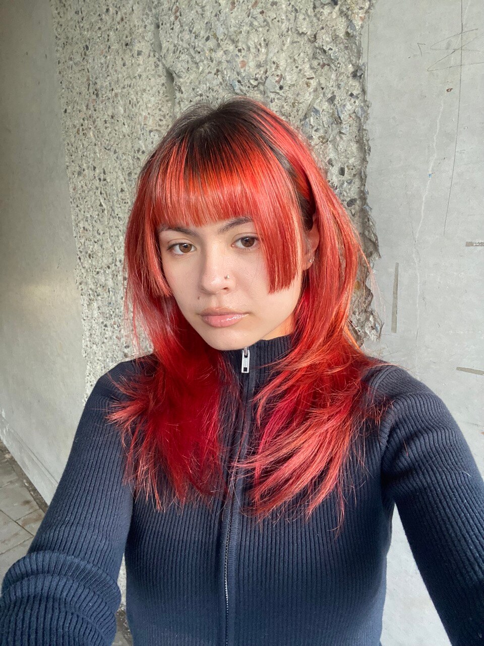 A selfie of a woman with red and black hair in a jagged haricut