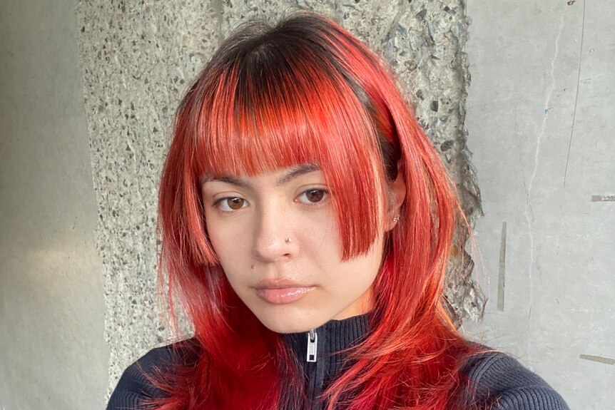 A selfie of a woman with red and black hair in a jagged haricut
