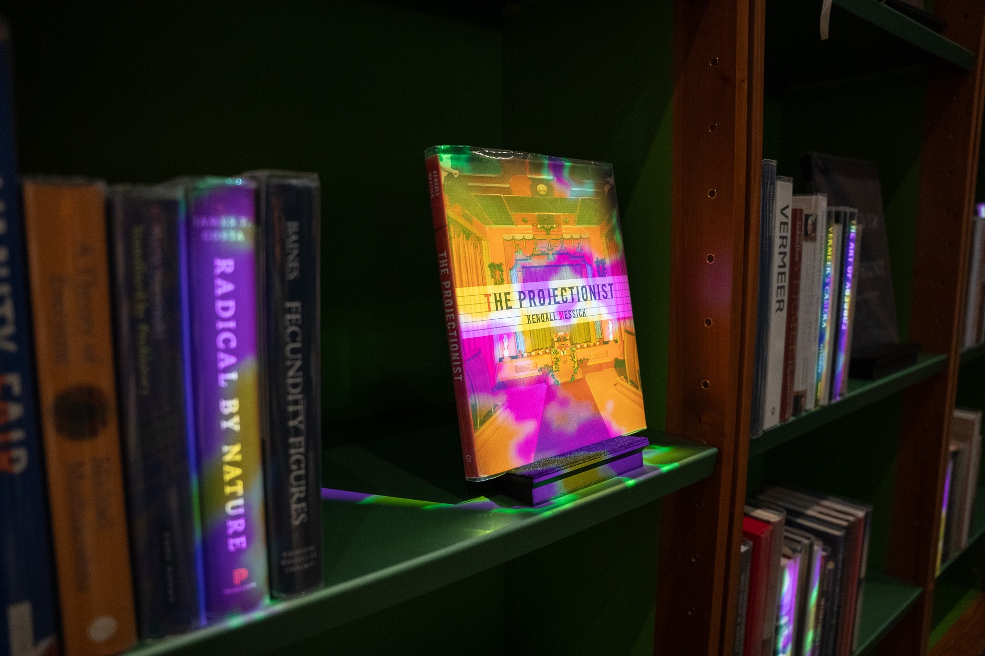 The shelves of a library, with some books lit up in neon colours.
