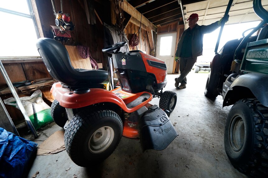 Trailer park owner Ed Smith looks at one of Geoffrey Holt's riding mowers.