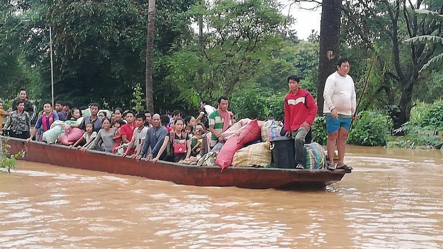 Dozens of people ride on a boat in flooded waters.