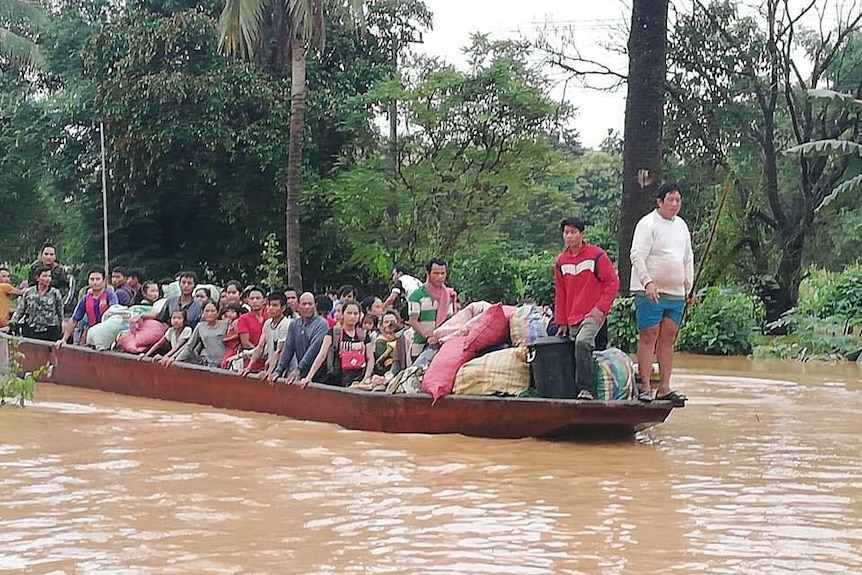 Dozens of people ride on a boat in flooded waters.