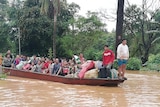 Dozens of people ride on a boat in flooded waters.