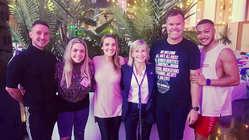 three men and three women standing arm in arm posing for a photo