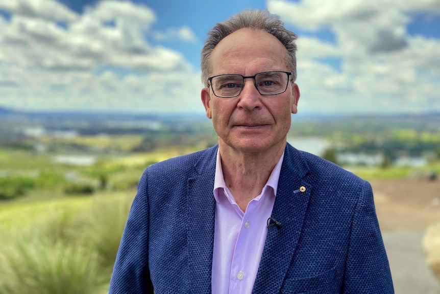 Jon stands looking serious, outside in Canberra where the fires once burned through.