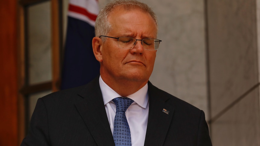 Scott Morrison stands with his eyes closed. 