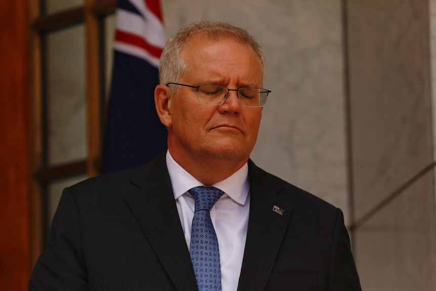 Scott Morrison stands with his eyes closed. 