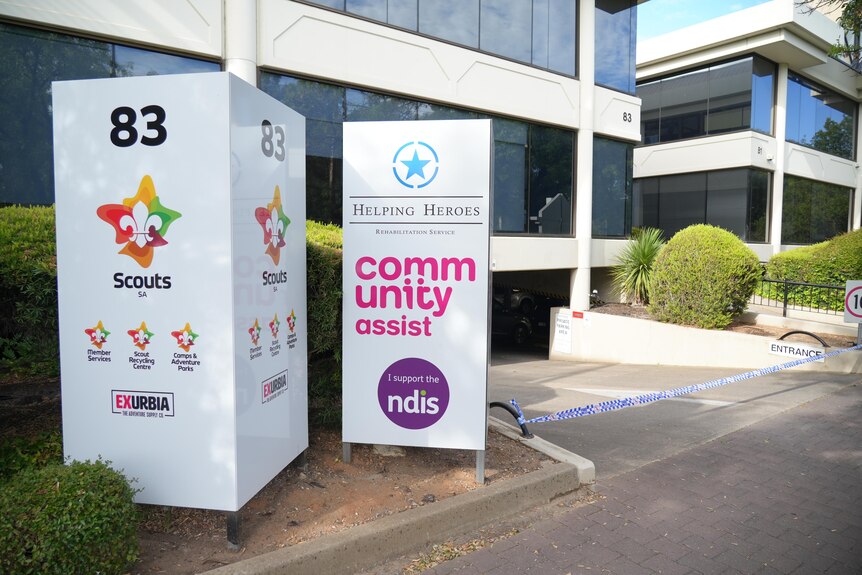 two signs of several charities erected at the entrance to an underground car par of a building