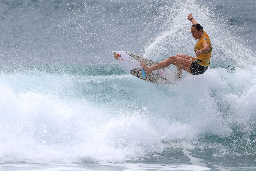 Hawaiian surfer Carissa Moore is surrounded by white spray as she cuts her board through the surf during a competition.
