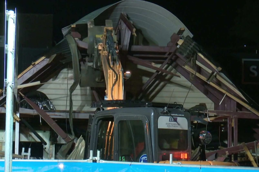 an excavator tearing into a building