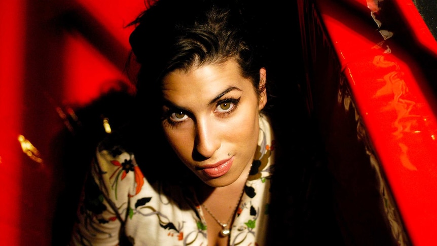 Singer Amy Winehouse looks up to camera with shadow across one side of her face