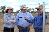 Premier Annastacia Palaszczuk, Wild Dog Fencing commissioner Vaughan Johnson and grazier John Macmillan standing behind a fence.
