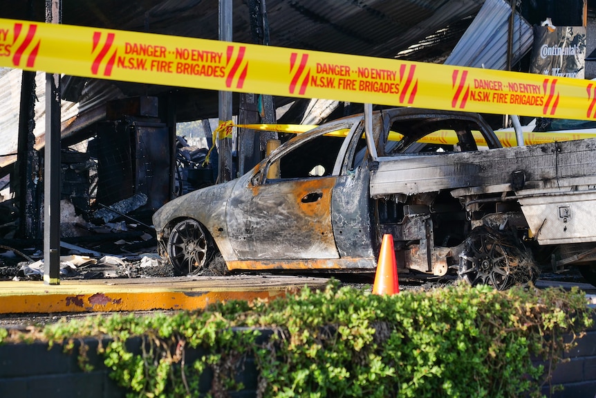A burnt out car at a tyre shop destroyed by fire