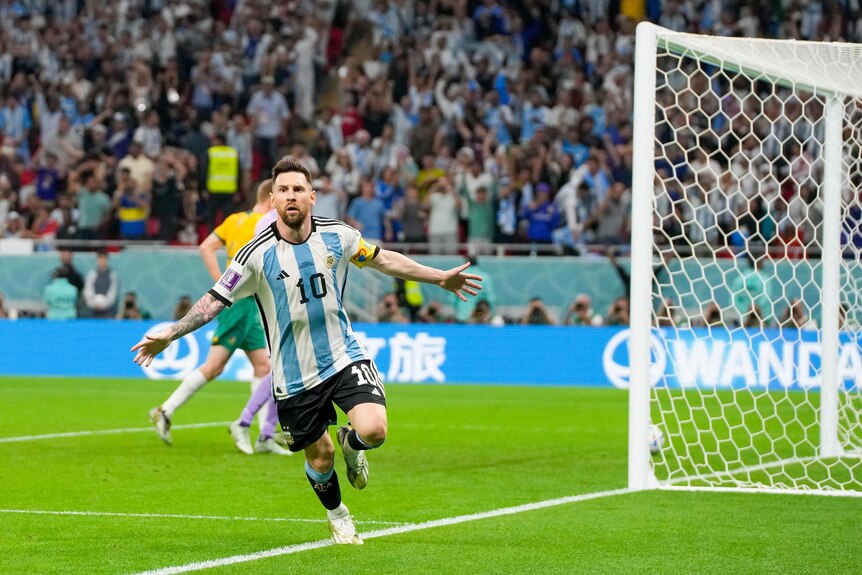 Argentina's Lionel Messi runs away from goal with his arms spread wide as the ball lies in the net.