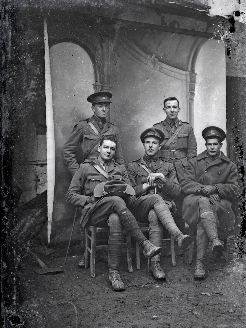 Five Australian soldiers pose in front of a backdrop in France during World War One.