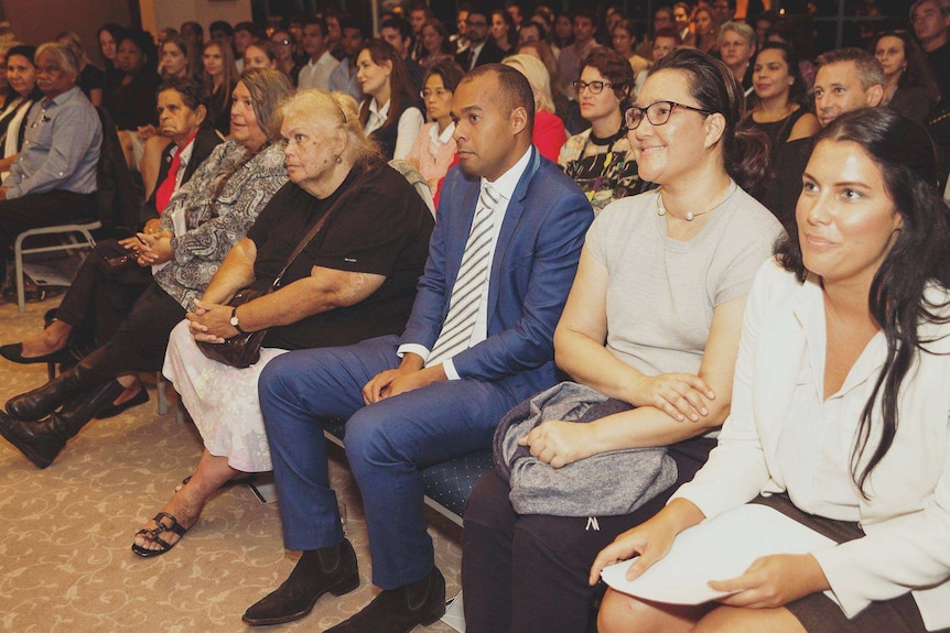 A group of people are seated watching ahead.