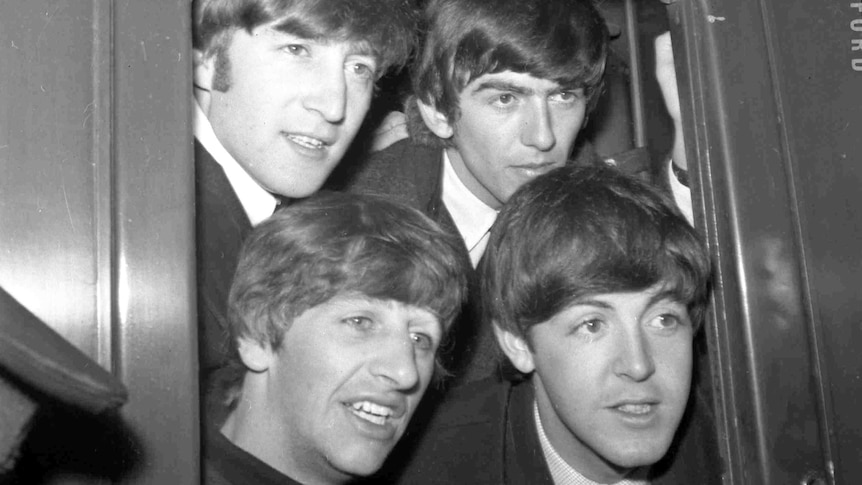 The Beatles pose in the window of train at Paddington Station in London