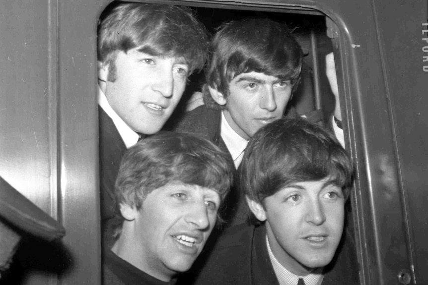 The Beatles pose in the window of train at Paddington Station in London