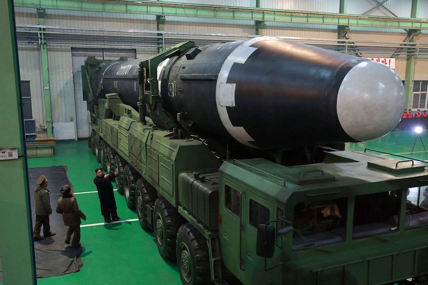 North Korean leader Kim Jong-un stands next to a massive truck holding a Hwasong-15 intercontinental ballistic missile