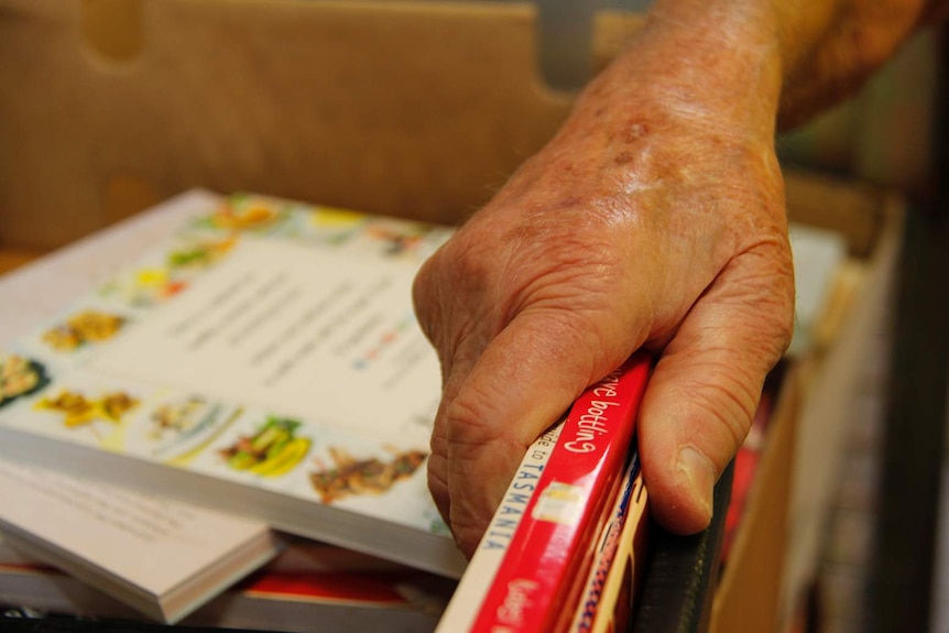 An old man's hand on some books.