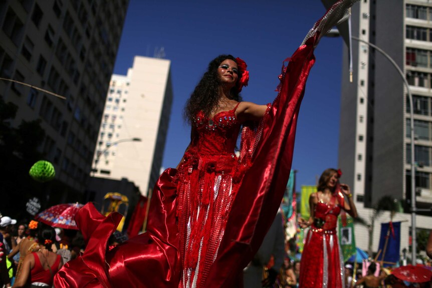 A woman wearing a sequined, red dress stands on stage during pre-Carnival celebrations in Rio de Janeiro.