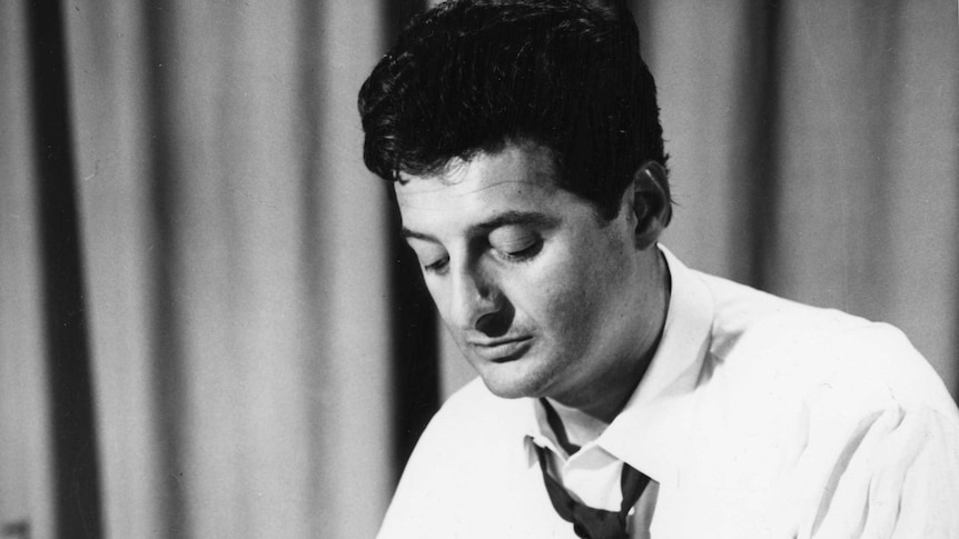 Black and white photo of a young Peter Sculthorpe composing at a desk.