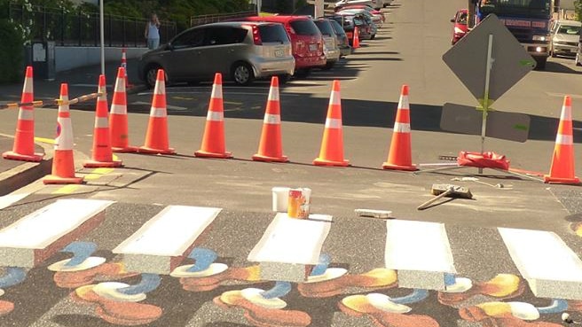 Optical illusion zebra crossing in Dunedin in New Zealand with feet underneath floating white lines