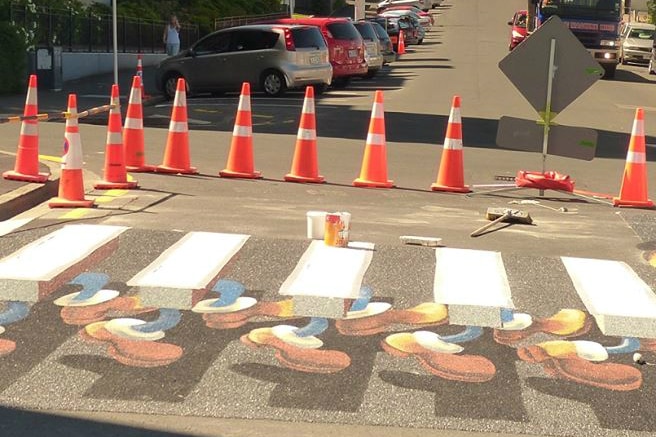 Optical illusion zebra crossing in Dunedin in New Zealand with feet underneath floating white lines