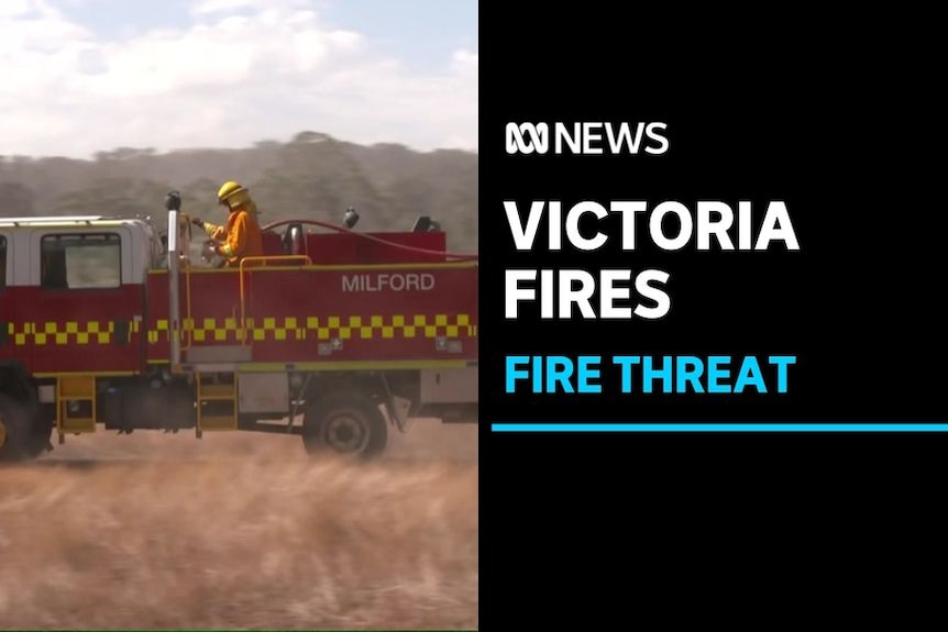 Victoria Fires, Fire Threat: Fire truck drives through dry landscape. A firefighter stands on the back of the truck.