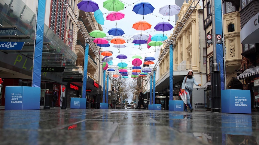 Colourful umbrellas hang above a Perth city mall and wet streets.