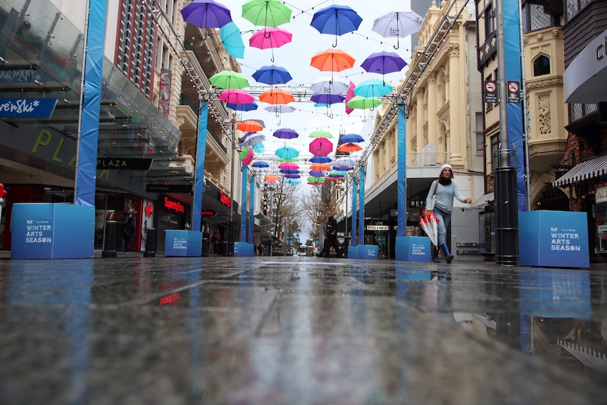 Colourful umbrellas hang above a Perth city mall and wet streets.